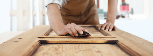 A professional sands a cabinet for finishing.